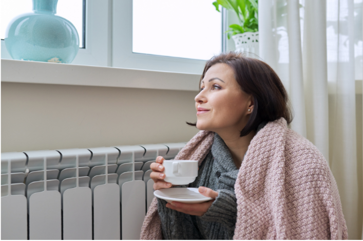 Woman staying warm indoors next to her heater