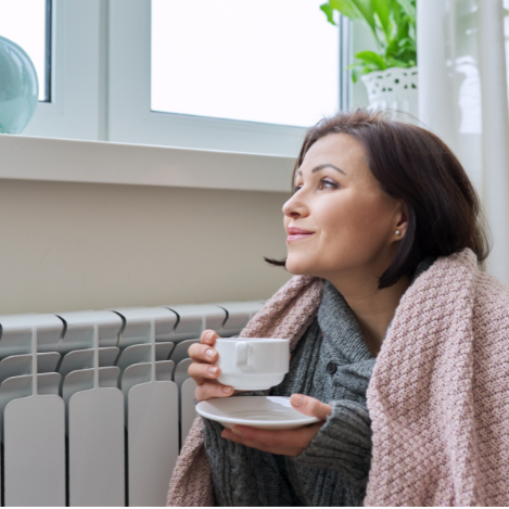 Woman staying warm indoors next to her heater